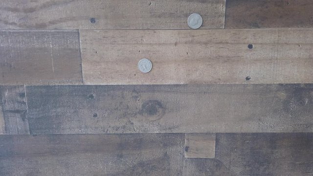 Coins falling one by one, on brown wood background, money and change concepts.