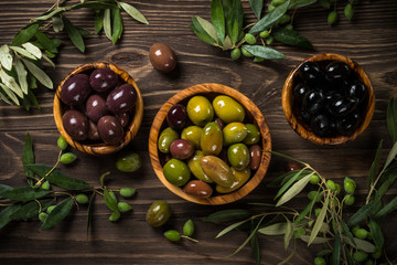 Black and green olives on wooden table.