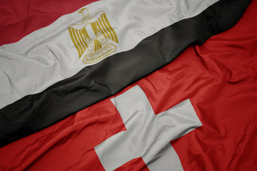 waving colorful flag of switzerland and national flag of egypt .