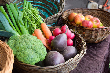 Baskets with fruits and vegetables on a local market counter. Apples, onions, beets, carrots, broccoli, radishes in baskets