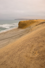 Dramatic coastline with intense colors in the desert of Paracas National Reserve, Peru