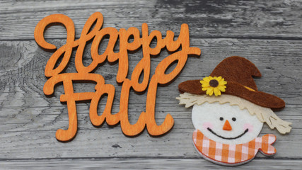 happy fall text, greeting card, fall image with happy scarecrow face laying flat on a grey rustic wood background. horizontal
