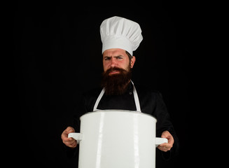 Male chef holds pot. Chef, cook or baker with saucepan in hand. Professional chef in uniform and hat holds pan. Cooking, food, profession concept. Chef in uniform cooking with cooking pot. Casserole.