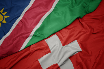 Obraz premium waving colorful flag of switzerland and national flag of namibia.