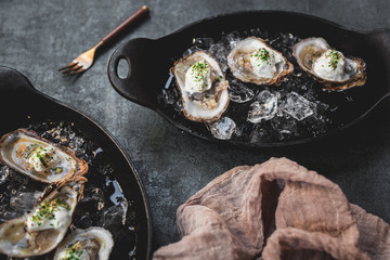 Raw oyster with mignonette sauce, celery & cream in cast iron on ice
