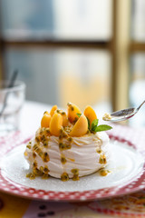 Mini Pavlova meringue cake with apricot and passion fruit on red polka dot plate