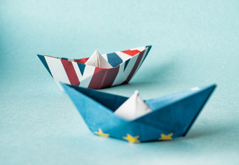 rust crack paper ships from the flags of the European Union and the UK on a blue background, concept of Brexit 