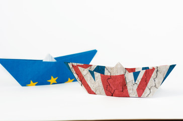 rust crack paper ships from the flags of the European Union and the UK on a blue background, concept of Brexit 