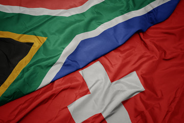 waving colorful flag of switzerland and national flag of south africa.