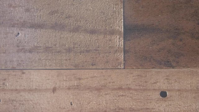 White D10 on brown wood background. Hand rolls a 4. 4k flat lay, slow.