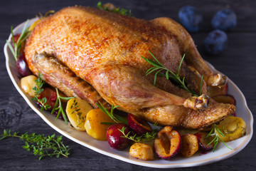 Whole duck with potatoes, plums and herbs