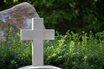 Weisses Kreuz aus Stein auf einer Wiese