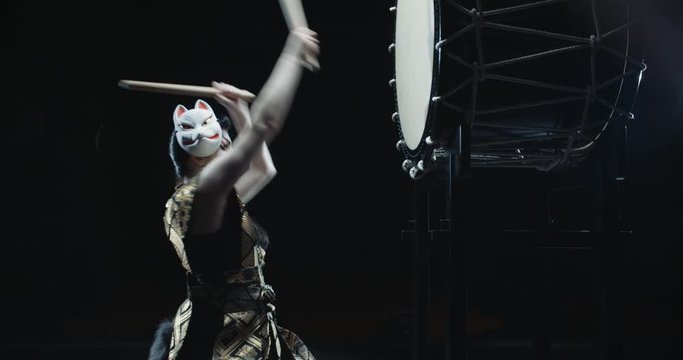 Female japanese drummer in traditional kitsune clothing playing on taiko drums, isolated on black background, - culture, tradition concept 4k footage