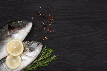 Fresh fish dorado. Dorado and ingredients for cooking on a black table.