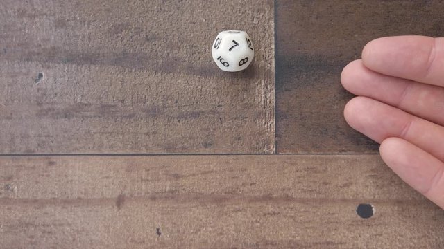 Hand rolls a 7 on twelve sided die, playing a game of luck and chance, 4k.