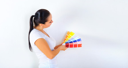 young girl holds a color palette in her hands and chooses a color for repairs in the house, on a white background