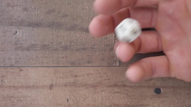 Examining a 12 sided dice in a hand, rotating, looking, spinning, up close, 4k.