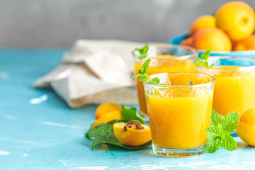 Glass of fresh healthy apricot juice in sunny light on blue surface