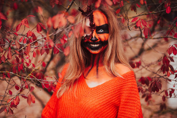 Young blonde girl with halloween face art posing outdoor.  Helloween celebration concept.