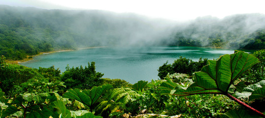 The turquoise green lagoon of Botos, in the Poas Volcano, Costa Rica, is surrounded by lush tropical vegetation.
