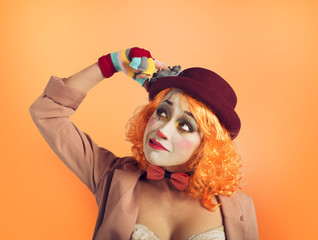 Pensive clown girl with too many questions. Orange background