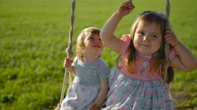 Faces of two girls swinging in a field on a rope swing close-up