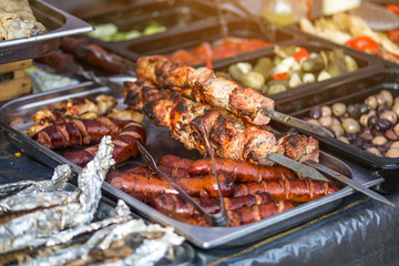 Barbecue fries in the coals. Blurred people eat at the table in the background. Meat and beef at the field kitchen festival.