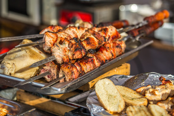 Barbecue fries in the coals. Blurred people eat at the table in the background. Meat and beef at the field kitchen festival.