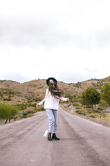 Obraz premium .happy woman with sombero dancing in the middle of an empty road in a rural area