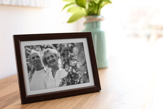 Portrait of senior couple in frame on table indoors. Space for text