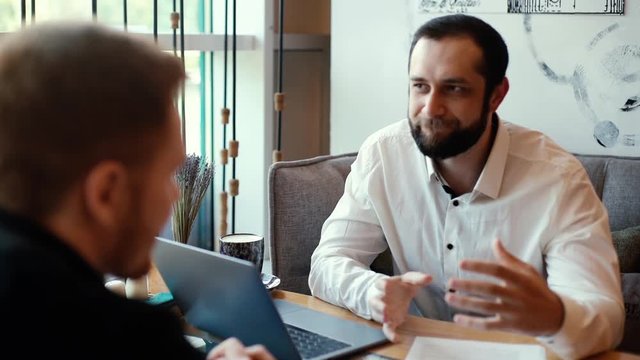 HR manager gives his opinion on candidate's CV for job. Confident businessman conducts interview with candidate for job. Shot in slow motion