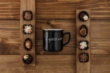 Side of black cup with title espresso on the brown wooden table with sweets