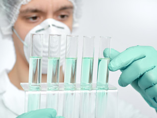 Keen scientist in protective wear with liquid samples