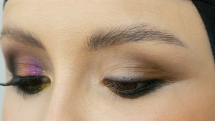 Professional stylist make-up artist makes eye makeup model. Face model with evening make-up close up view