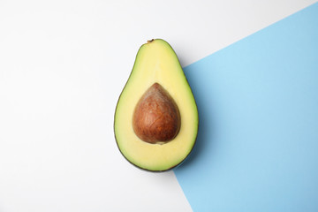 Cut fresh ripe avocado on color background, top view