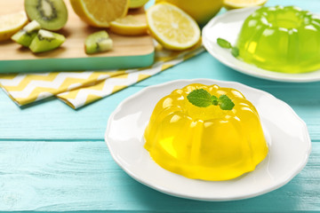 Plates of tasty fruit jelly on blue wooden table, space for text