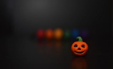 LGBT colored beads and Halloween pumpkin on black background soft focus