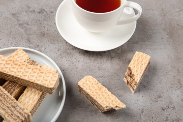 Fototapeta na wymiar Plate of delicious wafers with cup of tea on grey stone background