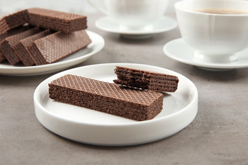 Delicious chocolate wafers with cup of coffee on grey stone background