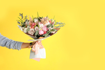 Man holding beautiful flower bouquet on yellow background, closeup view. Space for text
