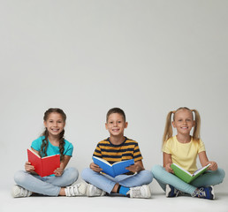 Little children reading books on grey background