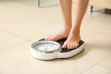 Woman standing on scales in bathroom. Overweight problem