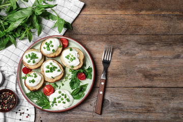 Delicious potato wedges with sour cream served on wooden table, flat lay. Space for text