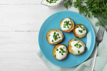 Delicious potato wedges with sour cream served on white wooden table, flat lay. Space for text