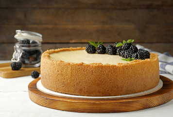 Delicious cheesecake decorated with blackberries on table