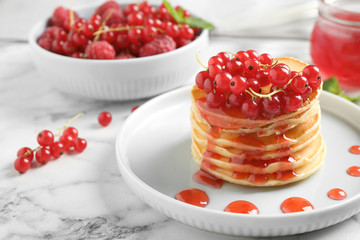 Delicious pancakes with fresh berries and syrup on white marble table