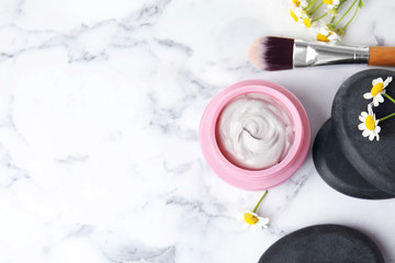 Professional face mask with brush, spa stones and flowers on white marble table, flat lay. Space for text