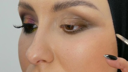Professional stylist make-up artist makes eye makeup model. Face model with evening make-up close up view