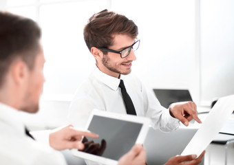 Obraz premium Team of two businessmen discussing new project using tablet and dokuments in the office.