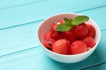 Bowl of watermelon balls with mint on light blue wooden table